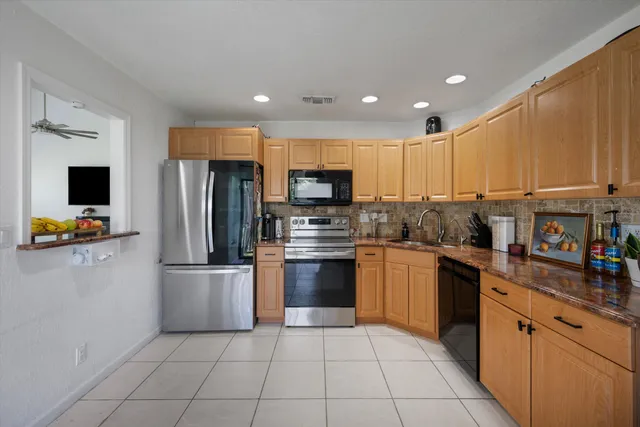 a kitchen with stainless steel appliances granite countertop a refrigerator and a stove top oven