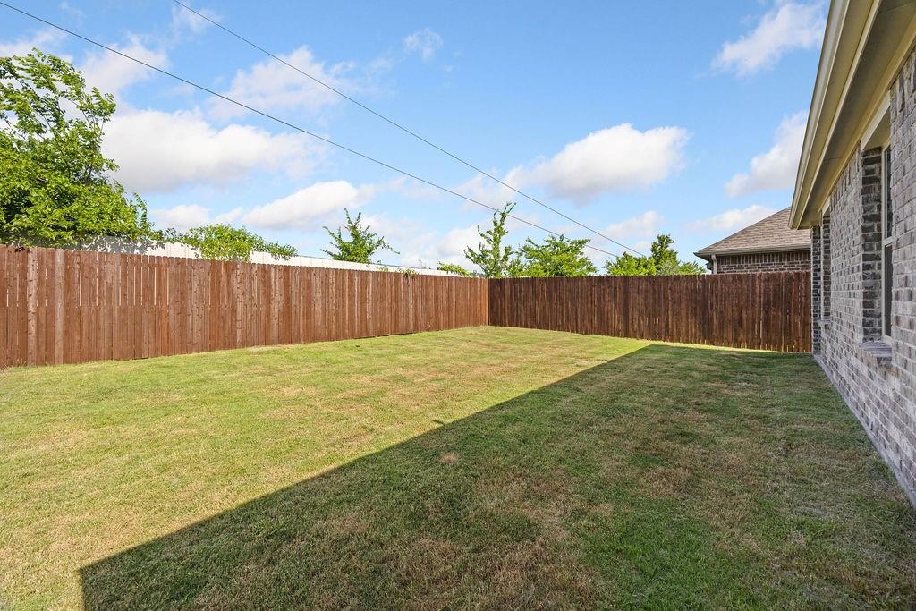 822 Ramble Road Lavon, TX 75166 - Photo 32 of 35 Expansive backyard featuring a manicured lawn, full privacy fencing, and a brick exterior facade