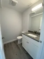 a bathroom with a granite countertop sink and a toilet