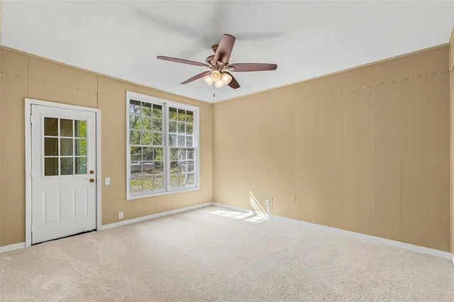 an empty room with a ceiling fan and a window