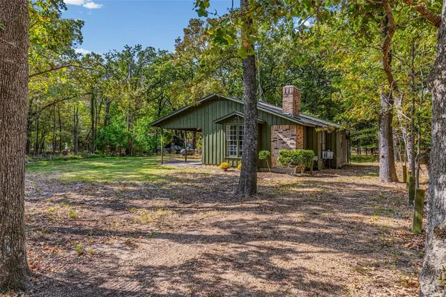 a view of a house with a yard and large tree