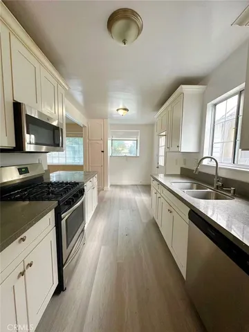 a large kitchen with stainless steel appliances granite countertop a stove a sink and a microwave