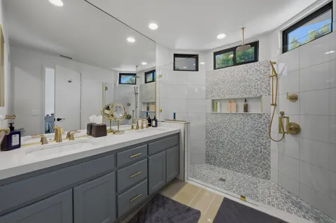 a en suite bathroom with a double vanity sink a mirror and shower