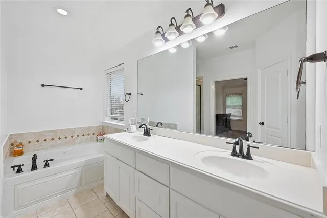 a bathroom with a double vanity sink mirror and bathtub