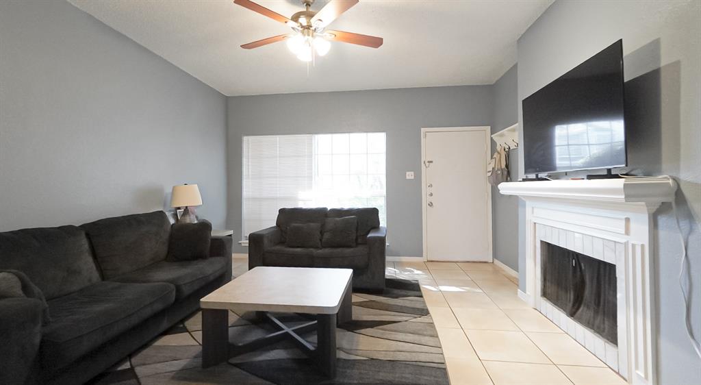 12921 Abrams Road, Unit 505 Dallas, TX 75243 - Photo 9 of 24 Living room with light tile patterned flooring, a fireplace, and ceiling fan