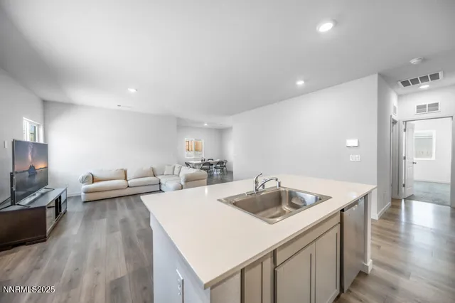 a large kitchen with kitchen island granite countertop a stove a sink a refrigerator and white cabinets with wooden floor