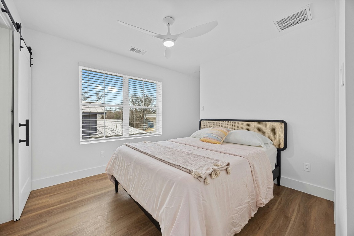 4704 Enchanted Lane, Unit B Austin, TX 78745 - Photo 12 of 23 a bedroom with a bed and a large window with wooden floor