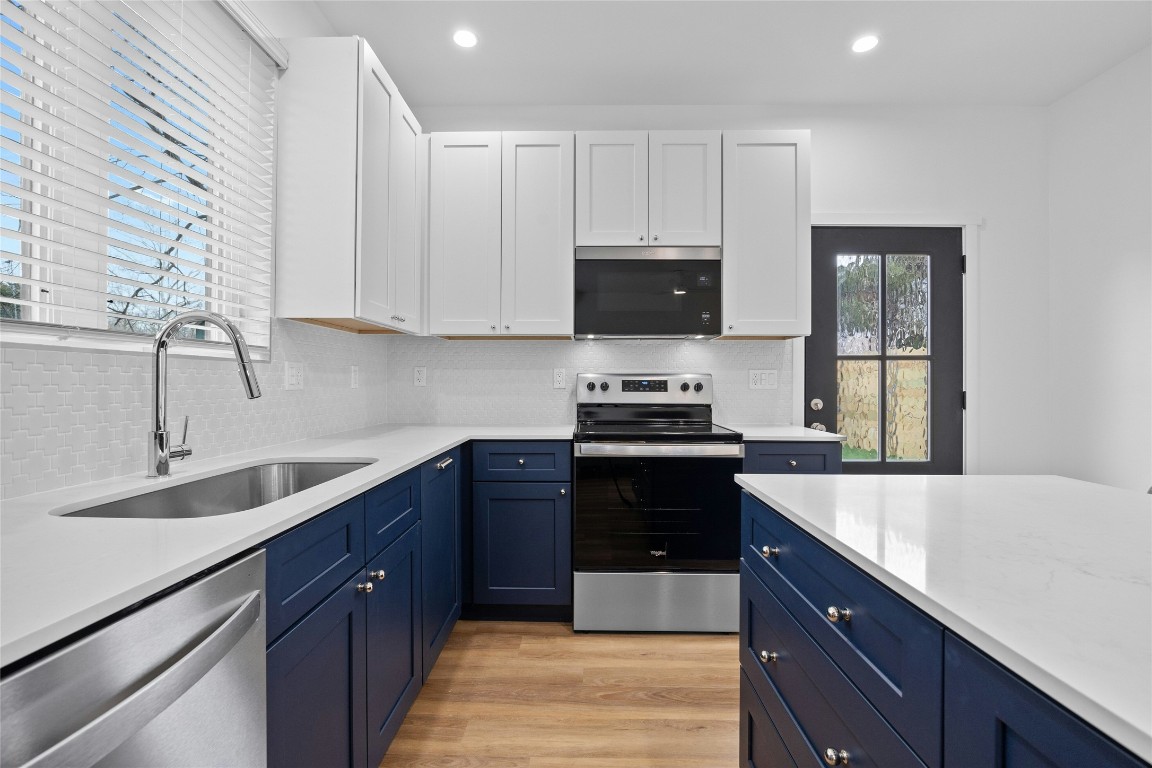 4704 Enchanted Lane, Unit B Austin, TX 78745 - Photo 7 of 23 a kitchen with kitchen island white cabinets appliances and a sink
