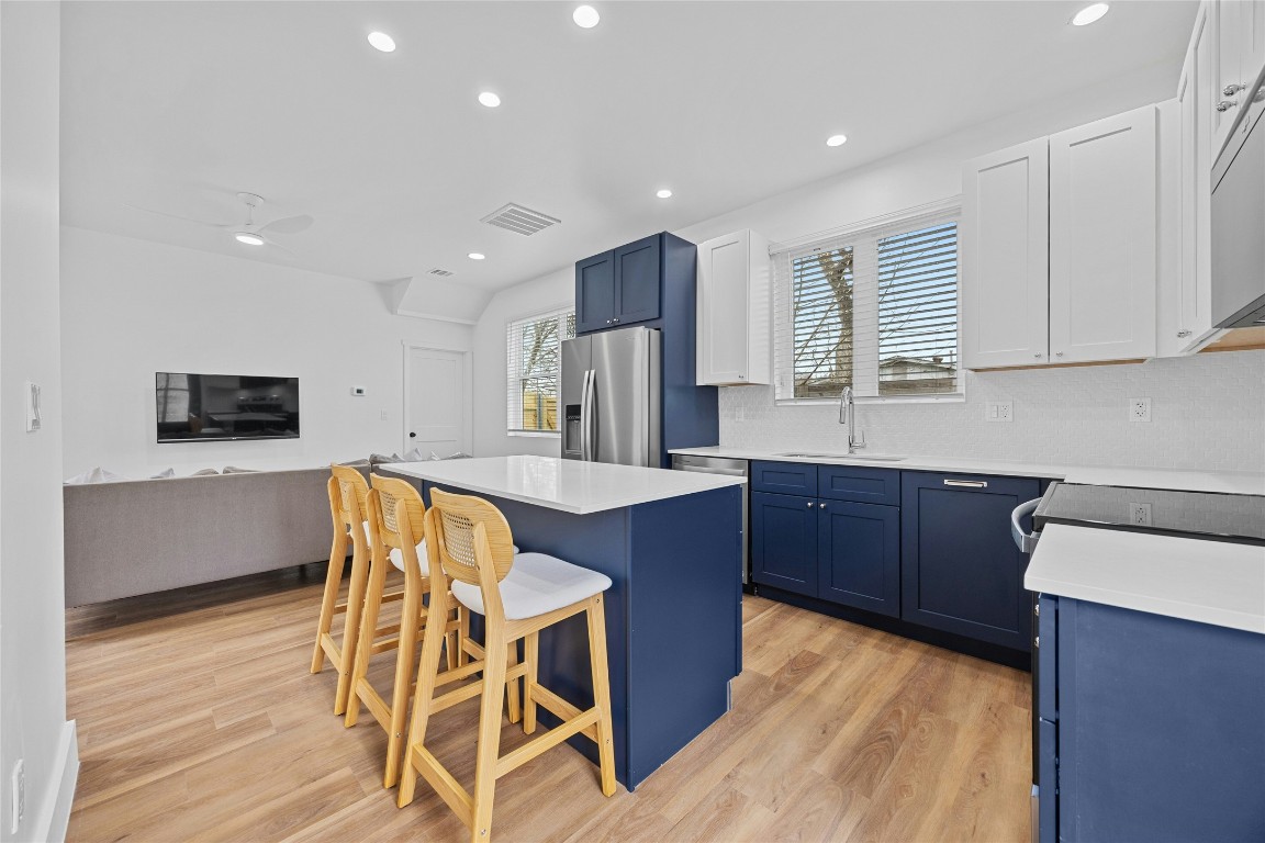 4704 Enchanted Lane, Unit B Austin, TX 78745 - Photo 9 of 23 a kitchen with stainless steel appliances kitchen island granite countertop wooden cabinets a stove a sink a dining table and chairs
