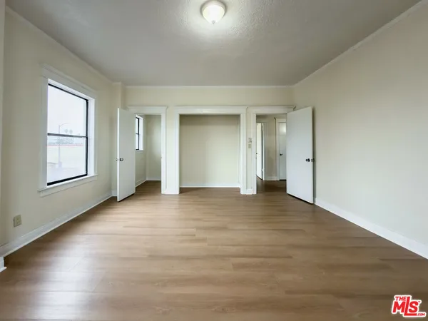 a view of an empty room with window and wooden floor