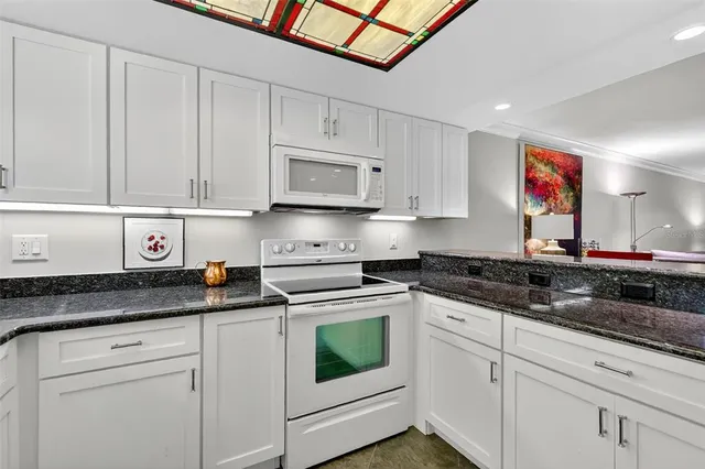 a kitchen with granite countertop white cabinets and white appliances