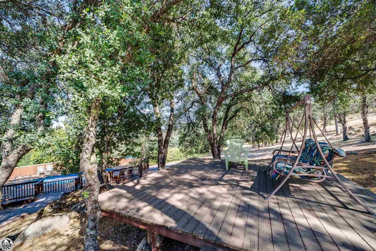 1801 Quail Hill Road Copperopolis, CA 95228 - Photo 33 of 42 a view of a patio with table and chairs and a barbeque with wooden fence and floor