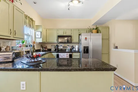 a kitchen with stainless steel appliances granite countertop a sink a refrigerator and a counter space