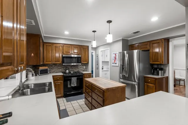 a kitchen with stainless steel appliances kitchen island granite countertop a refrigerator and a stove top oven