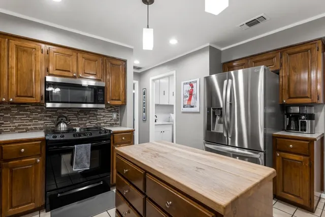 a kitchen with stainless steel appliances granite countertop a refrigerator stove top oven and sink