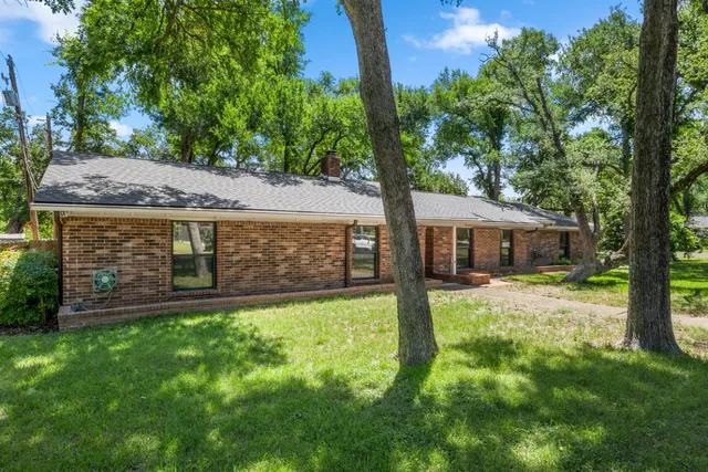 a view of a house with a large tree and a yard