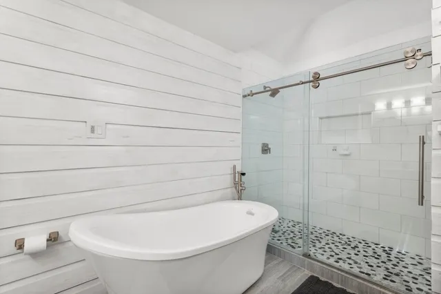 a white bath tub sitting next to a white toilet and vanity