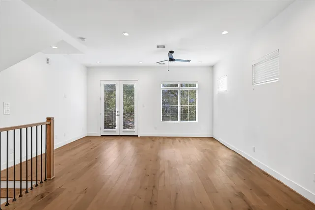 an empty room with wooden floor and windows