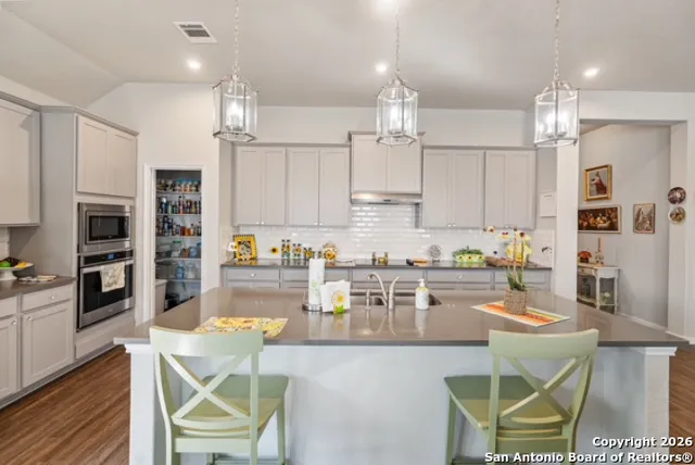 a kitchen with stainless steel appliances granite countertop a stove top oven a sink a dining table and chairs with wooden floor