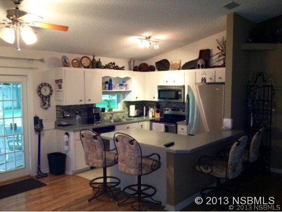 3224 Mango Tree Drive Edgewater, FL 32141 - Photo 8 of 17 a kitchen with stainless steel appliances a stove a refrigerator and a dining table with wooden floor