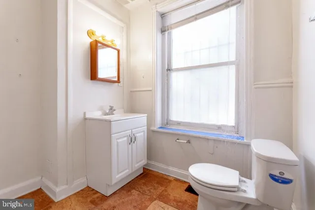 a bathroom with a sink toilet a mirror and window