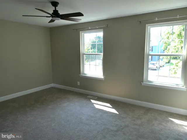 an empty room with a window and a fan