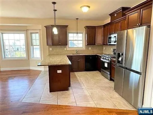 a large kitchen with kitchen island granite countertop wooden floor a refrigerator a sink and dishwasher