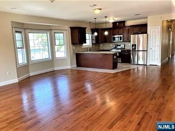 315 Frank E Rodgers Boulevard North, Unit 3 Harrison, NJ 07029 - Photo 3 of 18 a kitchen with stainless steel appliances granite countertop a refrigerator a sink dishwasher a stove and a wooden floor