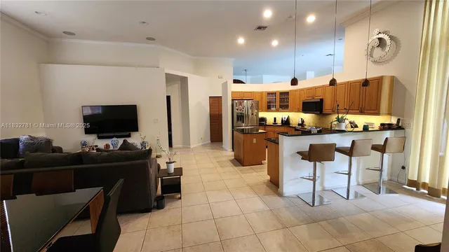 a living room with stainless steel appliances kitchen island granite countertop a table and chairs in it