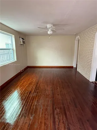 an empty room with wooden floor chandelier fan and windows