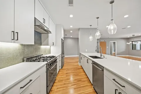 a large white kitchen with kitchen island a sink stainless steel appliances and cabinets