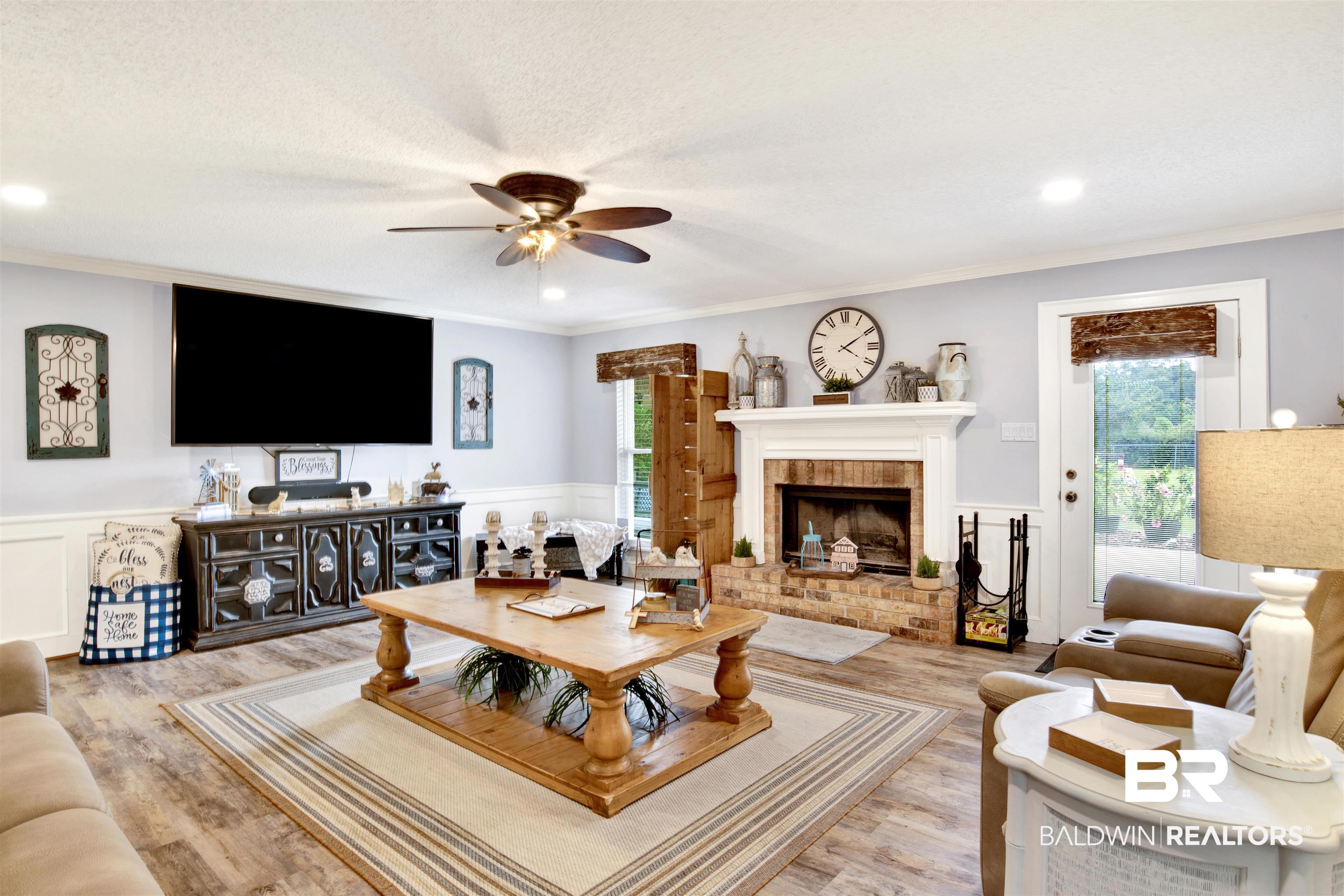 13385 Tom Gaston Road Mobile, AL 36695 - Photo 6 of 42 Living room featuring light hardwood / wood-style floors, a textured ceiling, a fireplace, ornamental molding, and ceiling fan