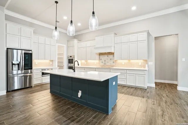 a kitchen with stainless steel appliances granite countertop a sink a stove a refrigerator and island with wooden floor