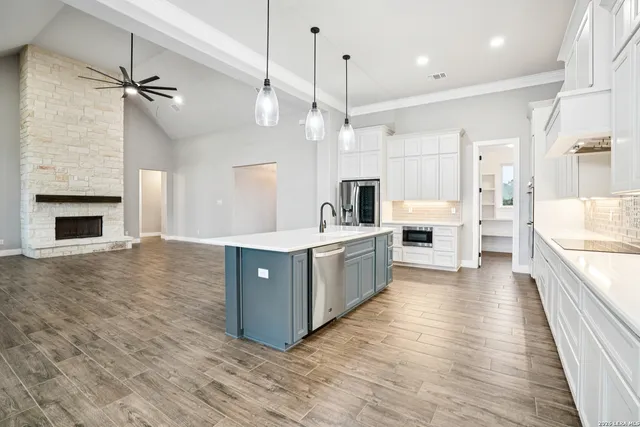 a large kitchen with kitchen island a stove a sink a refrigerator and a wooden floor