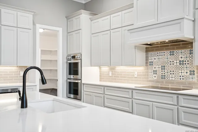 a kitchen with granite countertop a stove and white cabinets