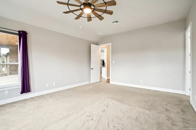 an empty room with a chandelier fan and wooden floor