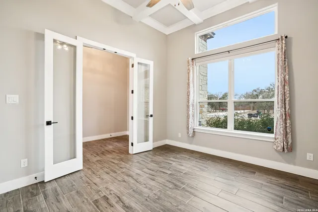 a view of an empty room with wooden floor and a window
