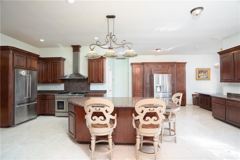 508 El Paisano Road Rio Grande City, TX 78582 - Photo 29 of 40 a kitchen with stainless steel appliances granite countertop a stove top oven a sink dishwasher a dining table and chairs with wooden floor