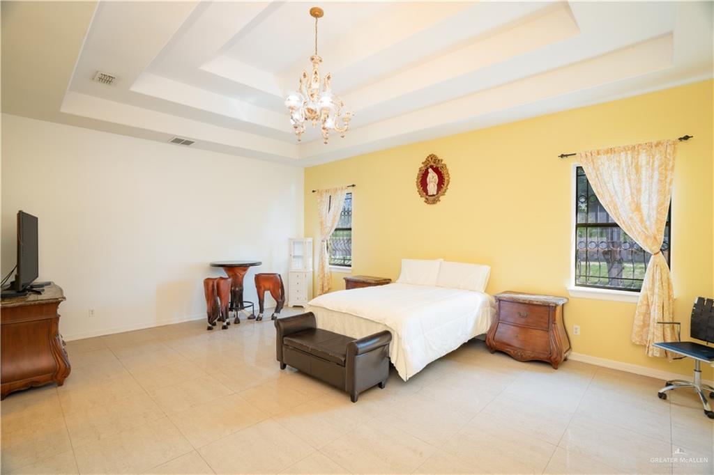 508 El Paisano Road Rio Grande City, TX 78582 - Photo 31 of 40 a spacious bedroom with a bed and a chandelier