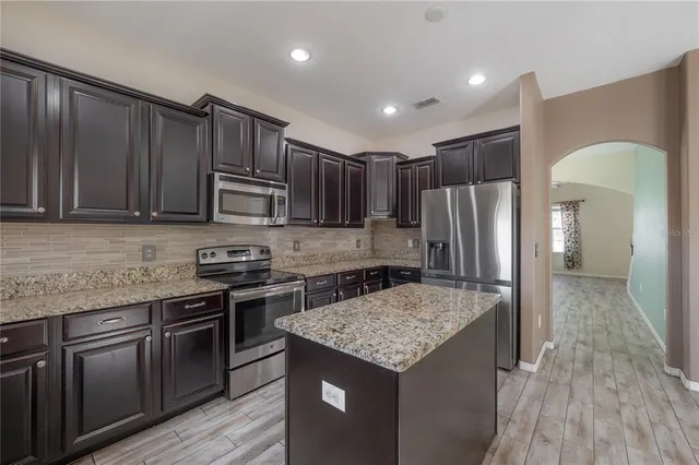 a kitchen with kitchen island granite countertop stainless steel appliances a sink stove and refrigerator
