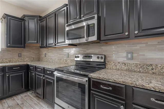 a kitchen with granite countertop a sink and steel appliances