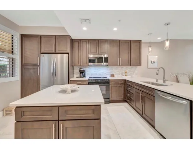 a kitchen with a sink a kitchen island and stainless steel appliances