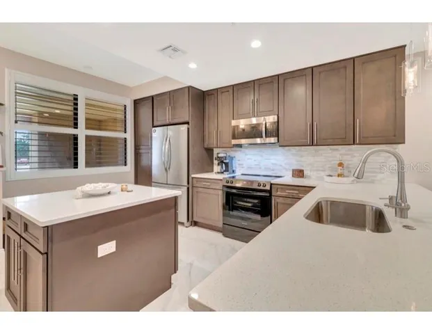 a kitchen that has a sink a stove and a refrigerator