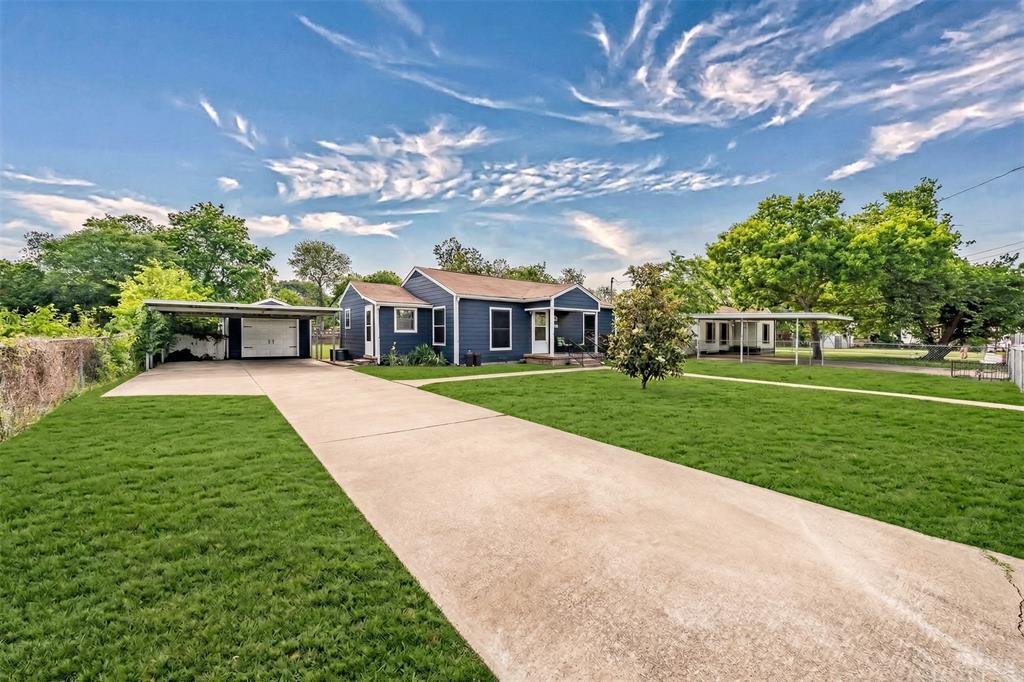 The property features a concrete driveway and an expansive lawn, leading to a blue exterior with white trim