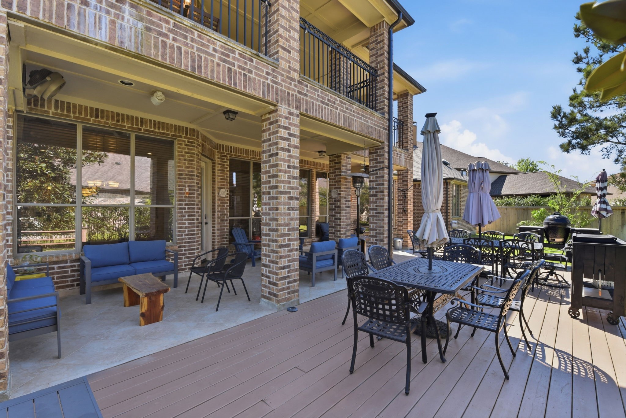 223 South Bauer Point Circle Spring, TX 77389 - Photo 35 of 50 This photo showcases a spacious outdoor patio area with stylish brickwork, comfortable seating, and a dining set perfect for entertaining. It includes a covered section for shade and a deck with ample space for gatherings, all set in a well-maintained backyard.