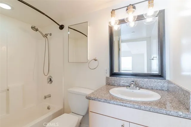 a bathroom with a granite countertop sink a mirror a shower and a bathtub