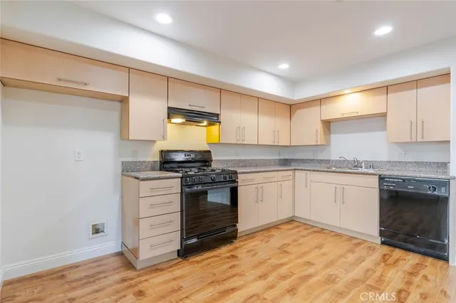 a kitchen with granite countertop a stove cabinets and wooden floor