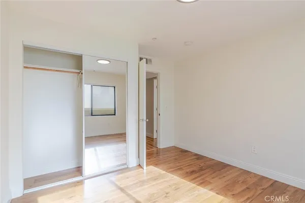 a view of a hallway with wooden floor and a bathroom