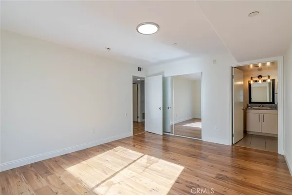a view of empty room with wooden floor and kitchen