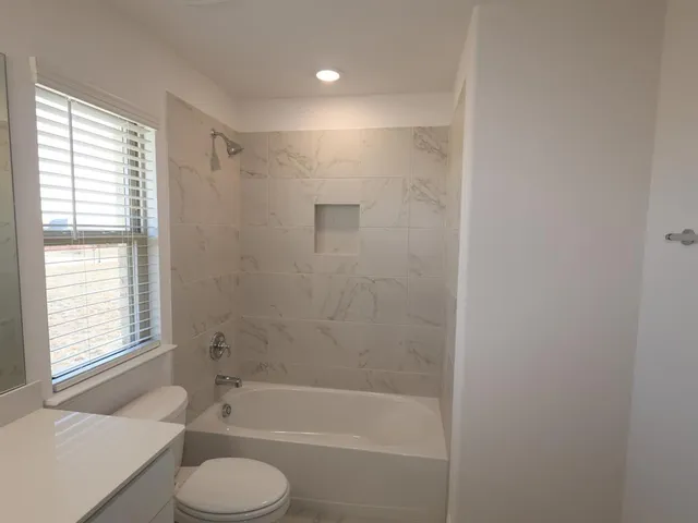 a bathroom with a shower a toilet and a tub